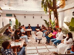 grupa ludzi siedzących w pokoju w obiekcie The Voyage - Cafe Hostel CoWork w mieście Pune