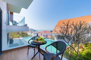 einen Balkon mit einem Tisch, Stühlen und einem Pool in der Unterkunft Cosa villages in Vũng Tàu