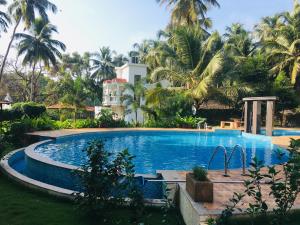 una piscina frente a una casa con palmeras en 2bhk Aqua Grandiosa Near Baga beach, en Arpora