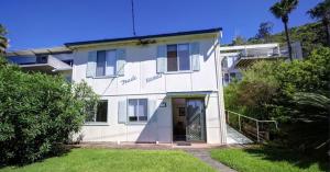 a white house with a door in a yard at Trade Winds in Elizabeth Beach