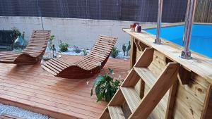 twee stoelen en een tafel op een houten terras naast een zwembad bij B&B Tra mare e montagna - sauna e piscina in San Giorgio di Pesaro