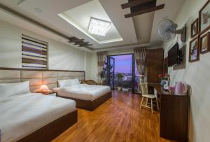 a hotel room with two beds and a desk and a window at Tasme Hotel in Da Lat