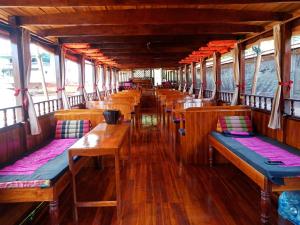 a train car with wooden tables and benches at Le Grand Cruise Package in Pakbeng