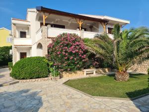 a house with a palm tree in front of it at Apartments Ivo in Pag
