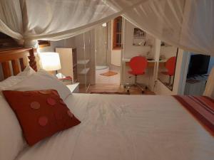 une chambre avec un lit blanc avec un oreiller rouge dans l'établissement Quirky Cottage in Centre of Maleny, Walk Everywhere, à Maleny