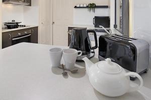 a kitchen counter with a tea kettle and cups on it at Terbium Sanctuary in Brisbane