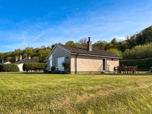 uma casa com um campo relvado em frente em Dykenamar em Kilchattan