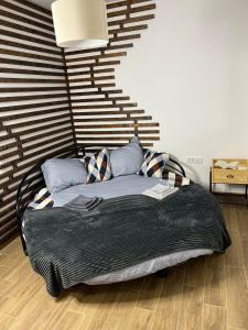 a bed with a black blanket and pillows in a room at In Dream Apartman in Inđija