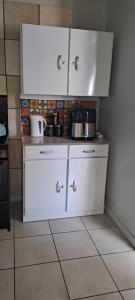 una cucina con armadietti bianchi, pentole e padelle di The Cottage Unit a Bloemfontein