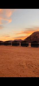 a sunset on a beach with mountains in the background at joy of life in Wadi Rum