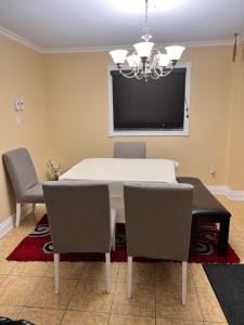 een eetkamer met een witte tafel en stoelen bij Faites comme chez vous in Gatineau