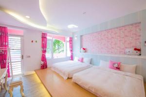 a bedroom with two beds and a pink wall at Qing Noise Villas in Hualien City