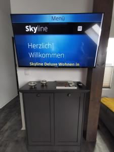 un televisor en la parte superior de un stand con una mesa en Skyline klimatisierte Dachgeschoss-Wohnung in Dornbirn mit Blick ins Rheintal en Dornbirn