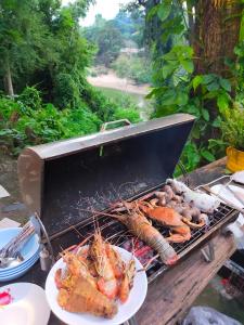 a grill with a plate of food on a table at Baanmai Phaipa House in Sai Yok