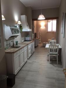 Emily house في بوزالو: مطبخ بدولاب بيضاء ومغسلة وطاولة