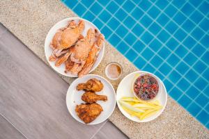 a table with two plates of food next to a swimming pool at so happy pool villa hua hin in Ban Bo Fai