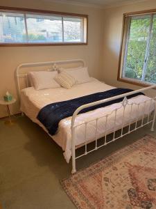 a bedroom with a white bed with a rug and two windows at Sandy Bay Villa in Sandy Bay