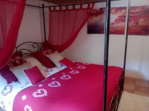 1 dormitorio con 1 cama con sábanas rosas y cortinas rojas en La Tranquilita, en Sospel