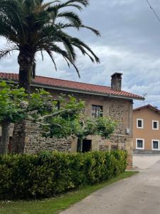 ein Gebäude mit einer Palme davor in der Unterkunft Casa vacacional Escuela la Llera in Colunga