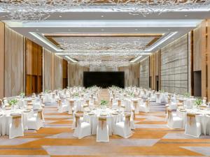 um grande salão de banquetes com mesas e cadeiras brancas em Sheraton Guangzhou Nansha Hotel em Guangzhou