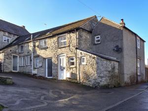 an old stone building on the side of a street at Corner Cottage in Great Longstone