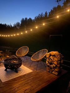 a deck with two chairs and a grill and lights at A Romantic & Luxurious stay in the nature of Karula National Park. in Ähijärve