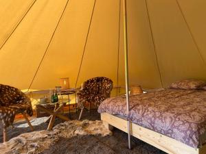 - une chambre avec un lit et deux chaises dans une tente dans l'établissement A Romantic & Luxurious stay in the nature of Karula National Park., à Ähijärve