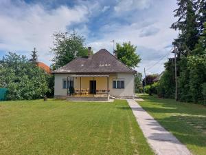 a small white house with a grass yard at Rozmaring apartman ház in Csopak