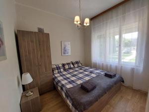 Habitación pequeña con cama y ventana en Rozmaring apartman ház, en Csopak