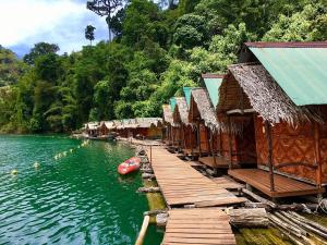 a row of huts on a dock on a river at Painting Family Hostel in Khao Sok