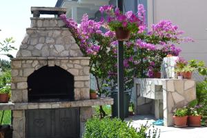 a stone fireplace in a yard with purple flowers at Apartments Milosevic in Bar