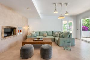 a living room with a green couch and two gray stools at Villa Amarantos in Santa Eularia des Riu