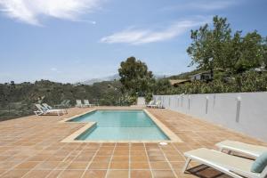 een zwembad op een patio met stoelen en een hek bij Finca Mojito in Cómpeta