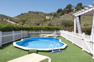 a swimming pool in a yard with a white fence at Casa Rural el Cerrillo in Cómpeta