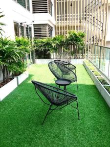 Deux chaises assises sur l'herbe dans un bâtiment dans l'établissement Lovely condo with swimming pool., à Bang Sare