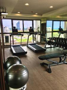 a gym with exercise equipment in a building with windows at Lovely condo with swimming pool. in Bang Sare
