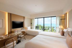 恩納村にあるハレクラニ沖縄のベッド2台とテレビが備わるホテルルームです。