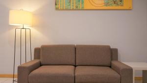 a couch sitting in a living room with a lamp at Marina Puteri Harbour Johor by Perfect Host in Nusajaya