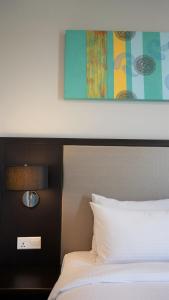 a bedroom with a white bed and a painting at Marina Puteri Harbour Johor by Perfect Host in Nusajaya