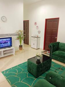 een woonkamer met een groene bank en een televisie bij Malin's Homestay Kota Bharu in Kota Bharu