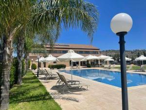a pool with chairs and umbrellas next to a building at Protaras Tennis and Country Club in Protaras
