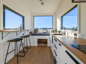 a kitchen with two large windows and a bench with stools at Glamping Vineyard Getaway with Luxury Amenities in Broke