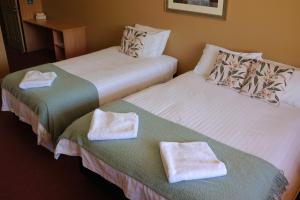 two beds in a hotel room with towels on them at Kendenup Cottages and Lodge in Kendenup