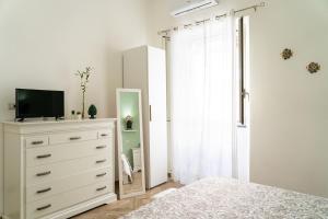 una camera da letto bianca con cassettiera e specchio di B&B Portosalvo a Santa Teresa di Riva