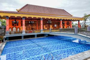 a swimming pool in front of a house with a building at Ramada Suites By Wyndham Solo in Solo