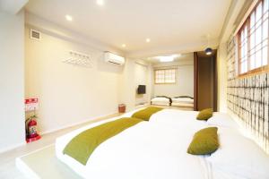 a bedroom with a large white bed with green pillows at Estate Kuromon Bekkan E in Osaka