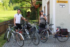 zwei Frauen stehen mit ihren Fahrrädern vor einem Haus in der Unterkunft Pension Wenger in Kirchheim im Innkreis