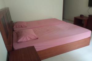 uma cama com lençóis cor-de-rosa e uma moldura de madeira em OYO 92696 Bahagia Homestay Syariah 