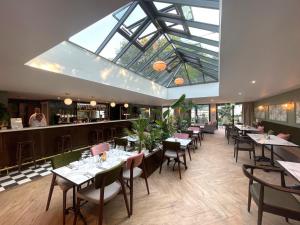 un restaurante con mesas y sillas y un tragaluz grande en Lydiard Park Hotel & Conference Centre, en Swindon