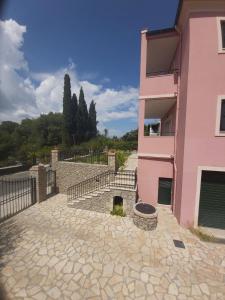 a pink house with a fire pit in front of it at Kanoni Apartment in Corfu Town